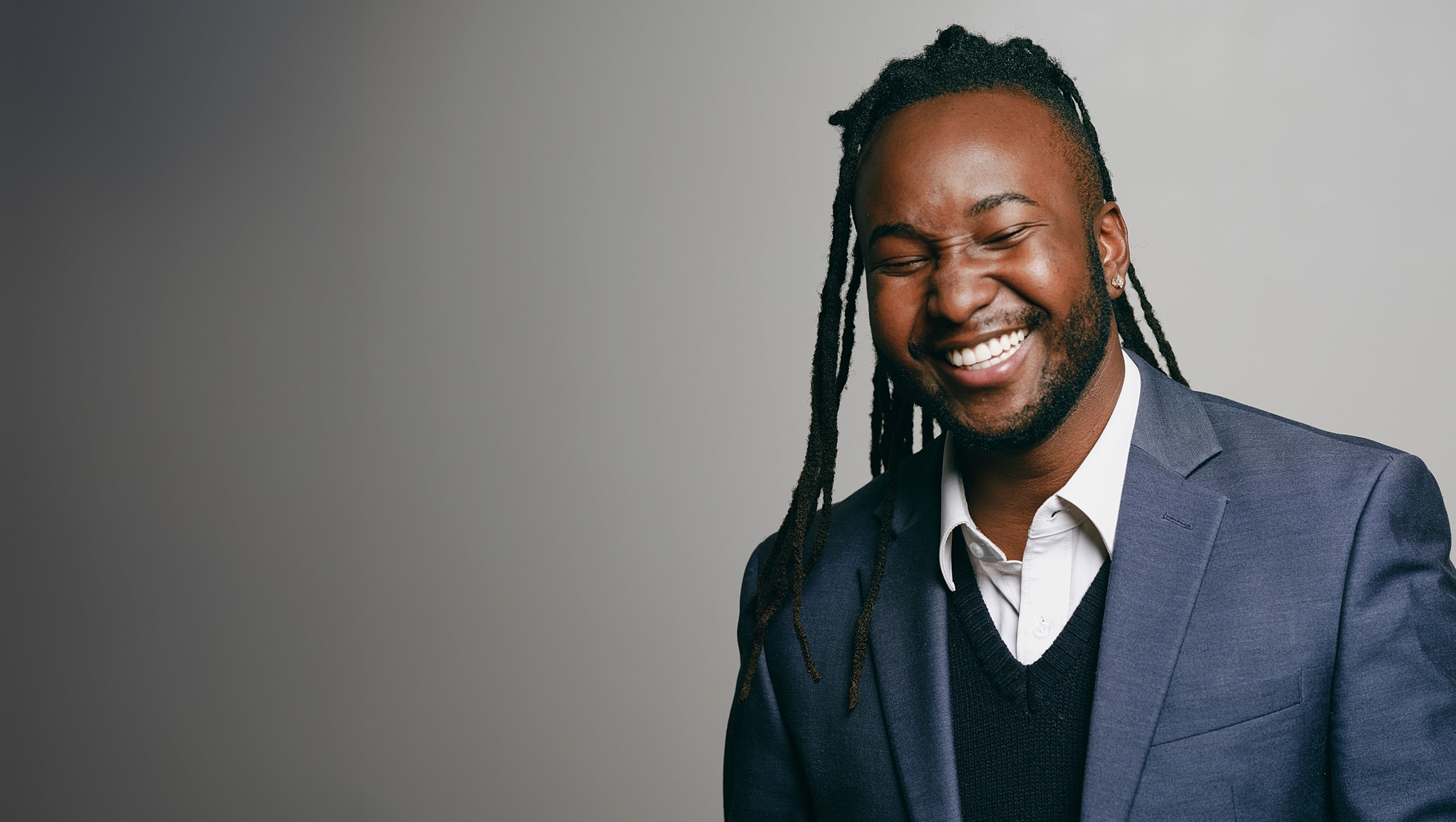 Smiling man in a suit against gray background.