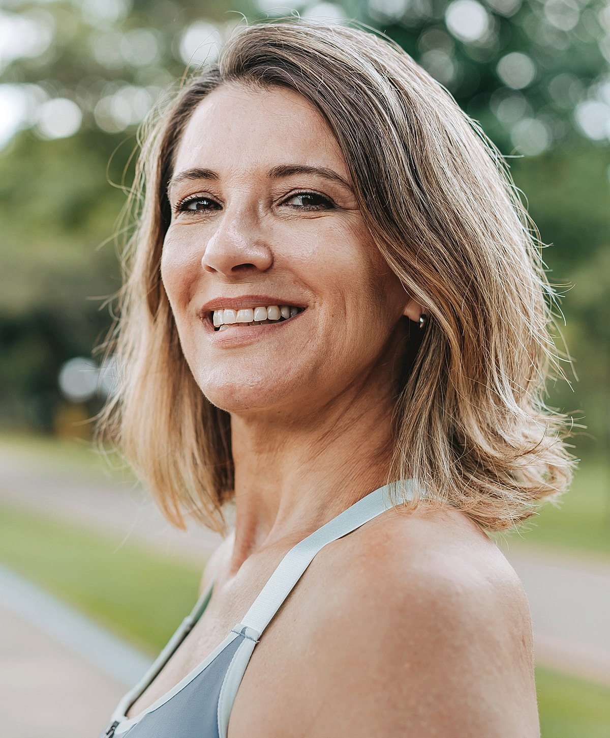 Smiling woman outdoors in athletic attire.
