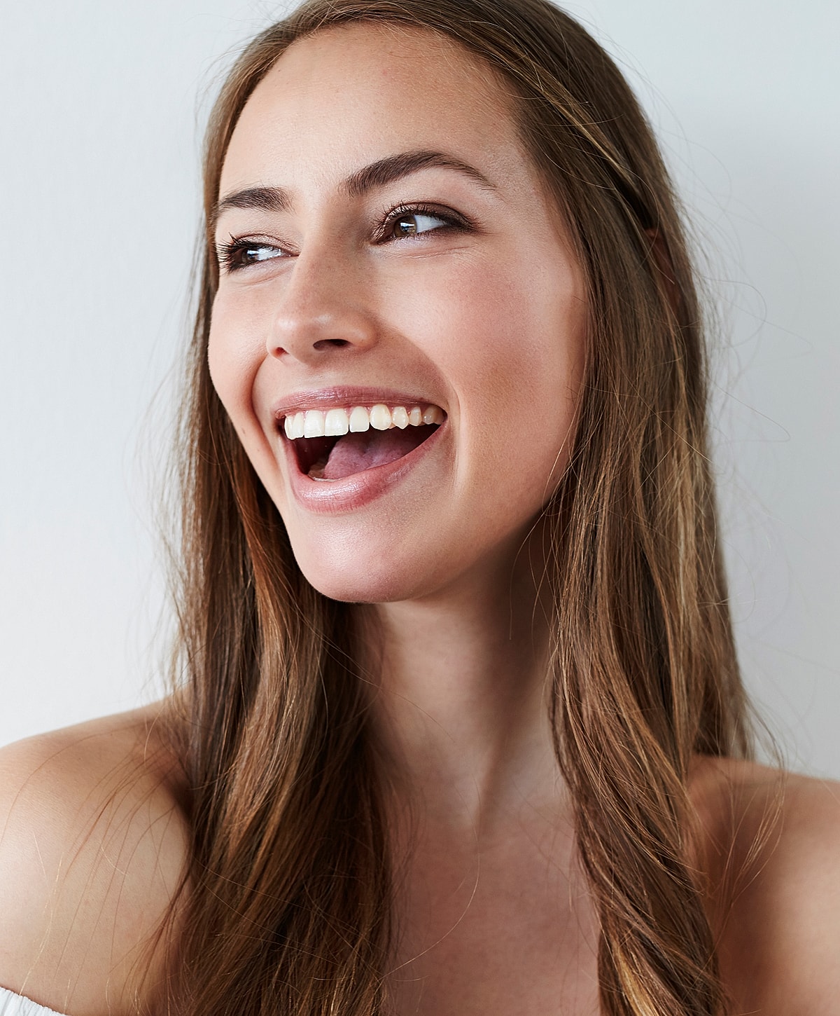 Smiling woman with long hair against a white background.