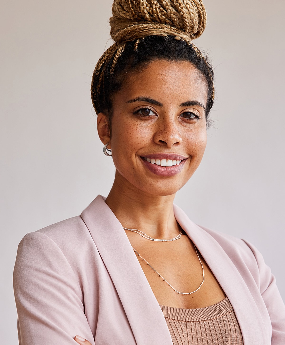 Smiling woman in a pink blazer and jewelry.