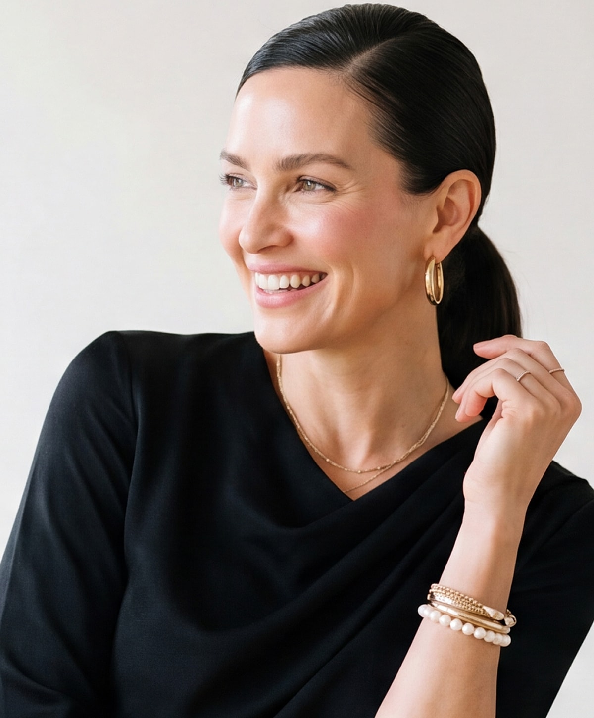 Smiling woman in black top with accessories.