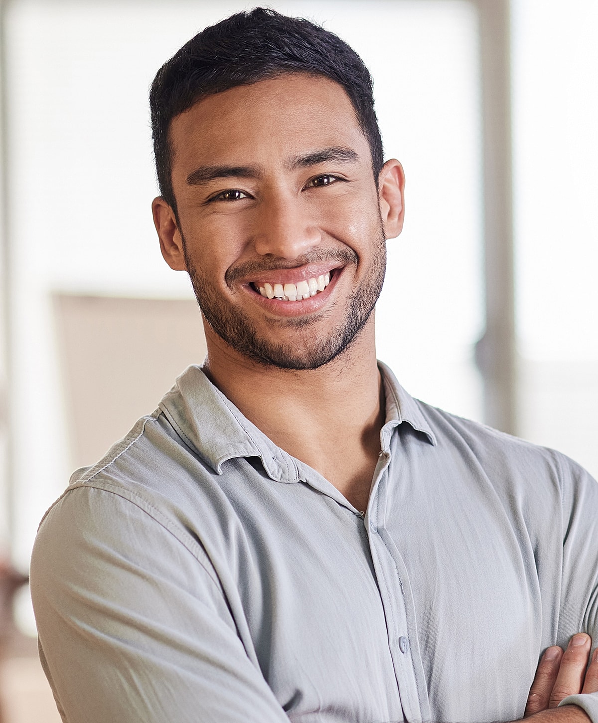 Smiling man with crossed arms indoors.