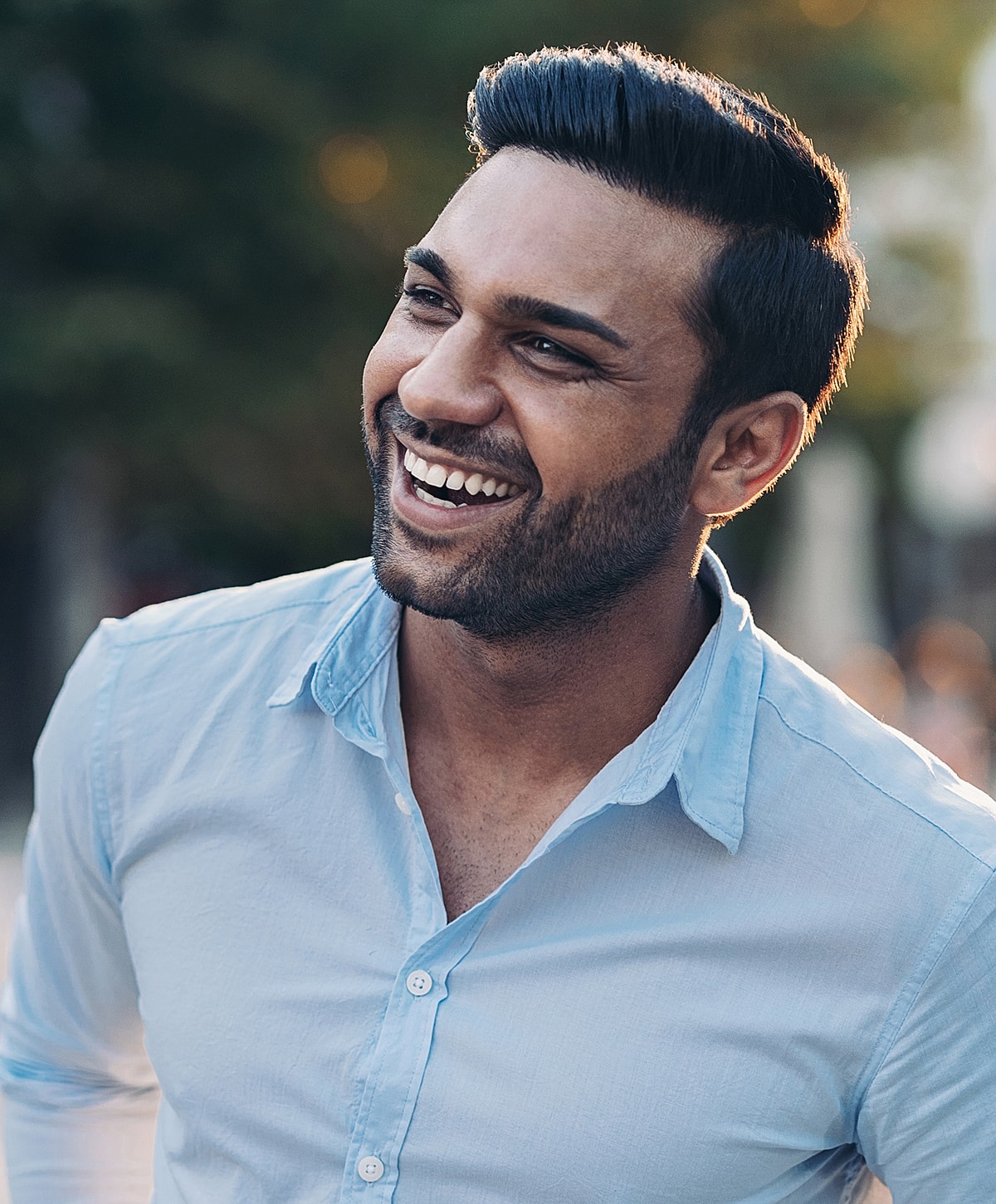 Smiling man in light blue shirt outdoors