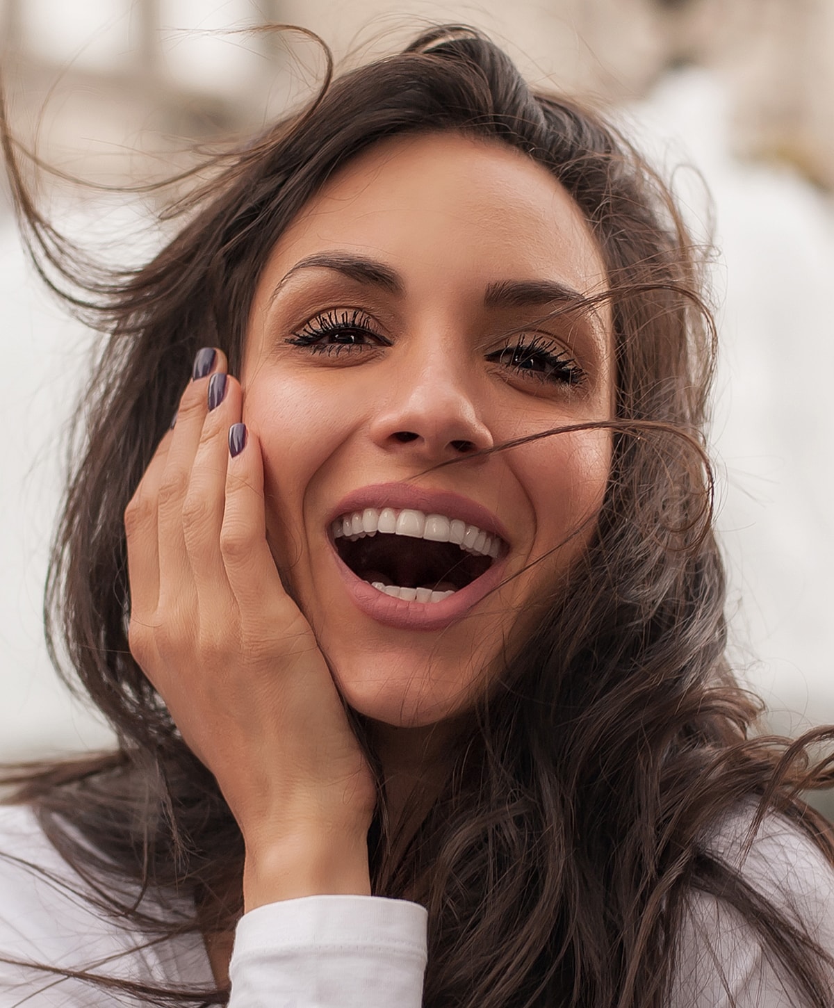 Smiling woman with flowing hair and joyful expression.