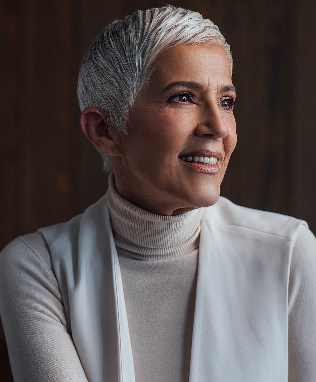 Smiling woman with short gray hair, elegant attire.