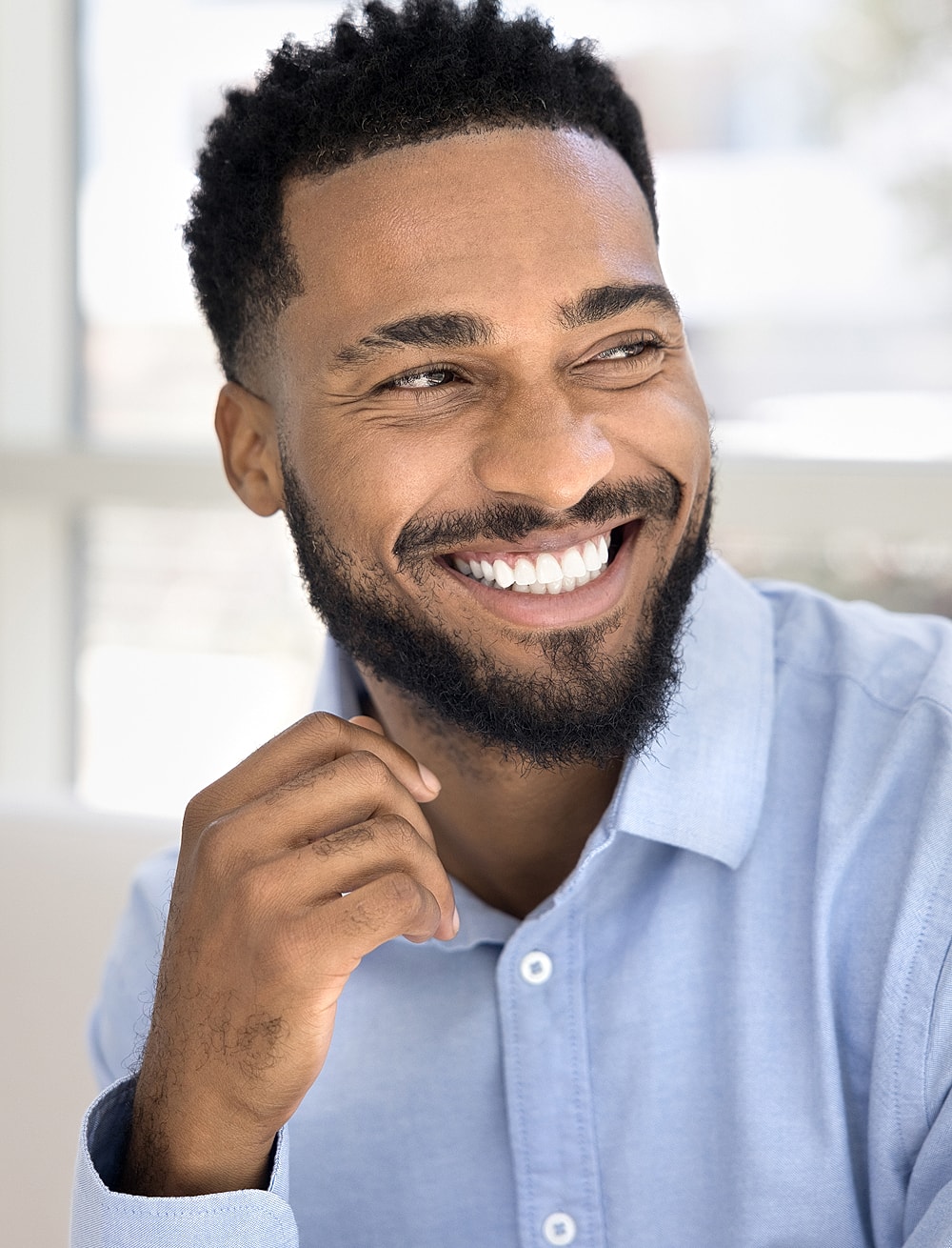 Smiling man in light blue shirt, relaxed vibe.