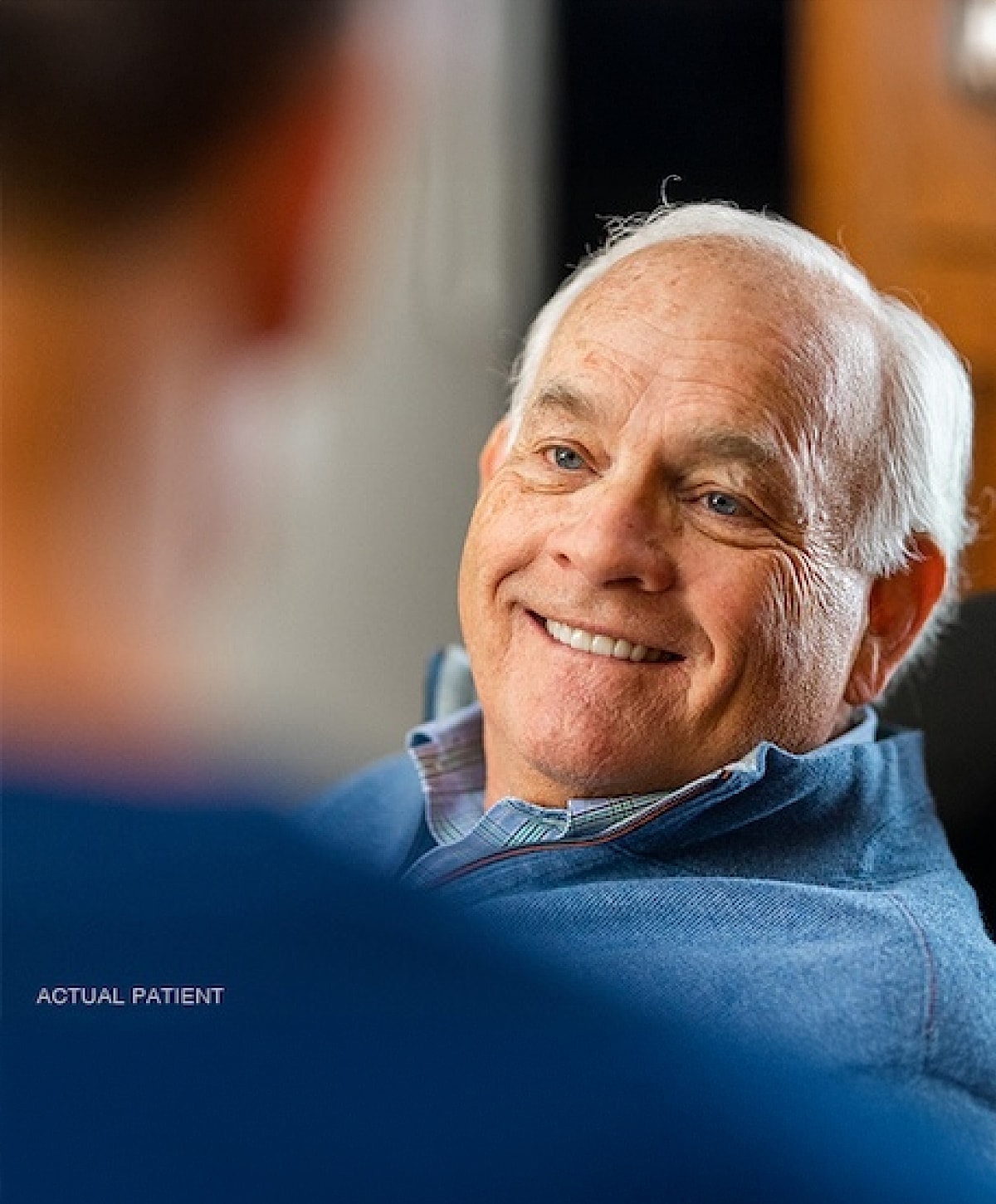 Smiling older man in casual attire, engaging conversation.