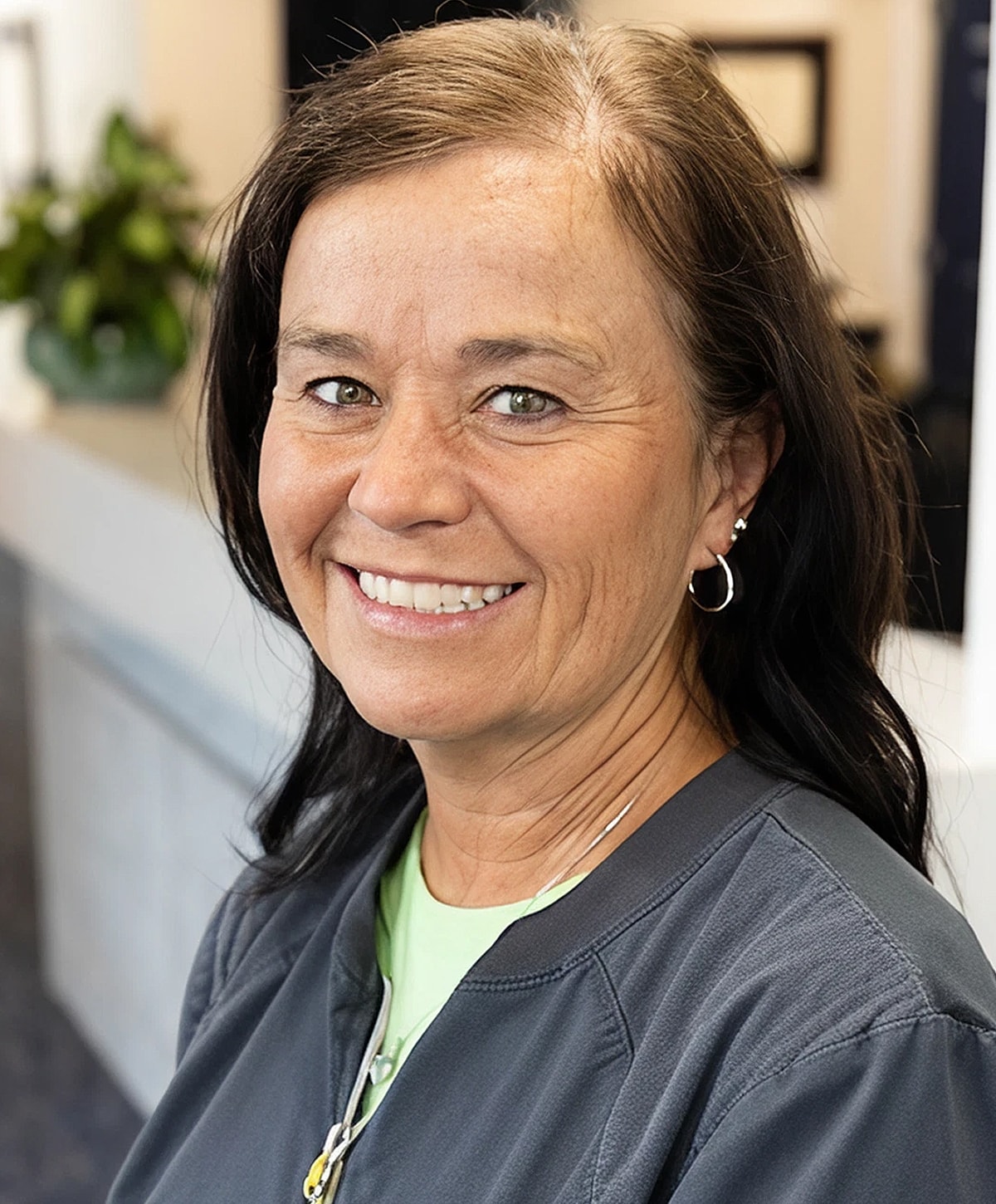 Smiling woman in professional attire with natural background.