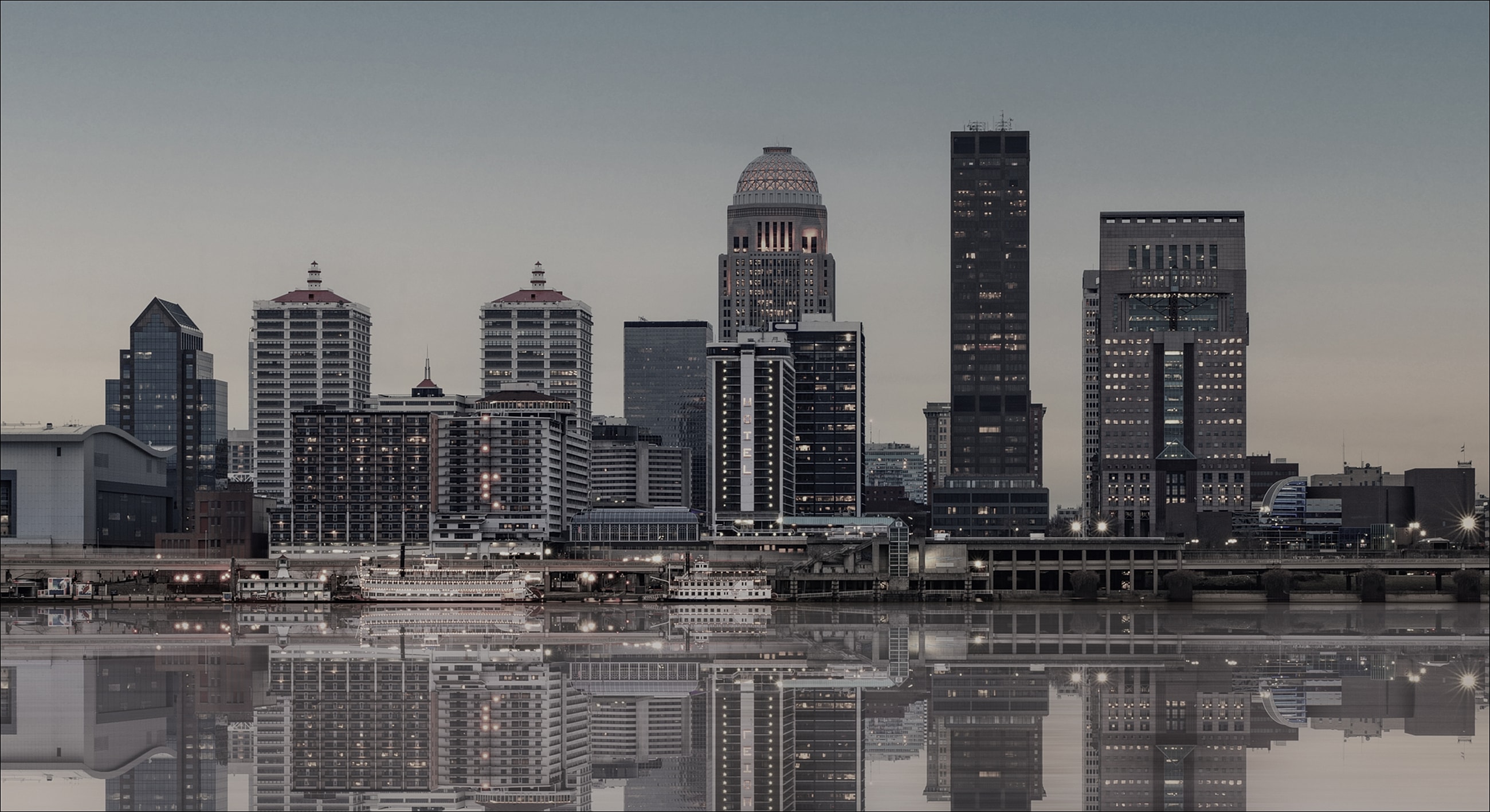 City skyline reflected in calm water at dusk.