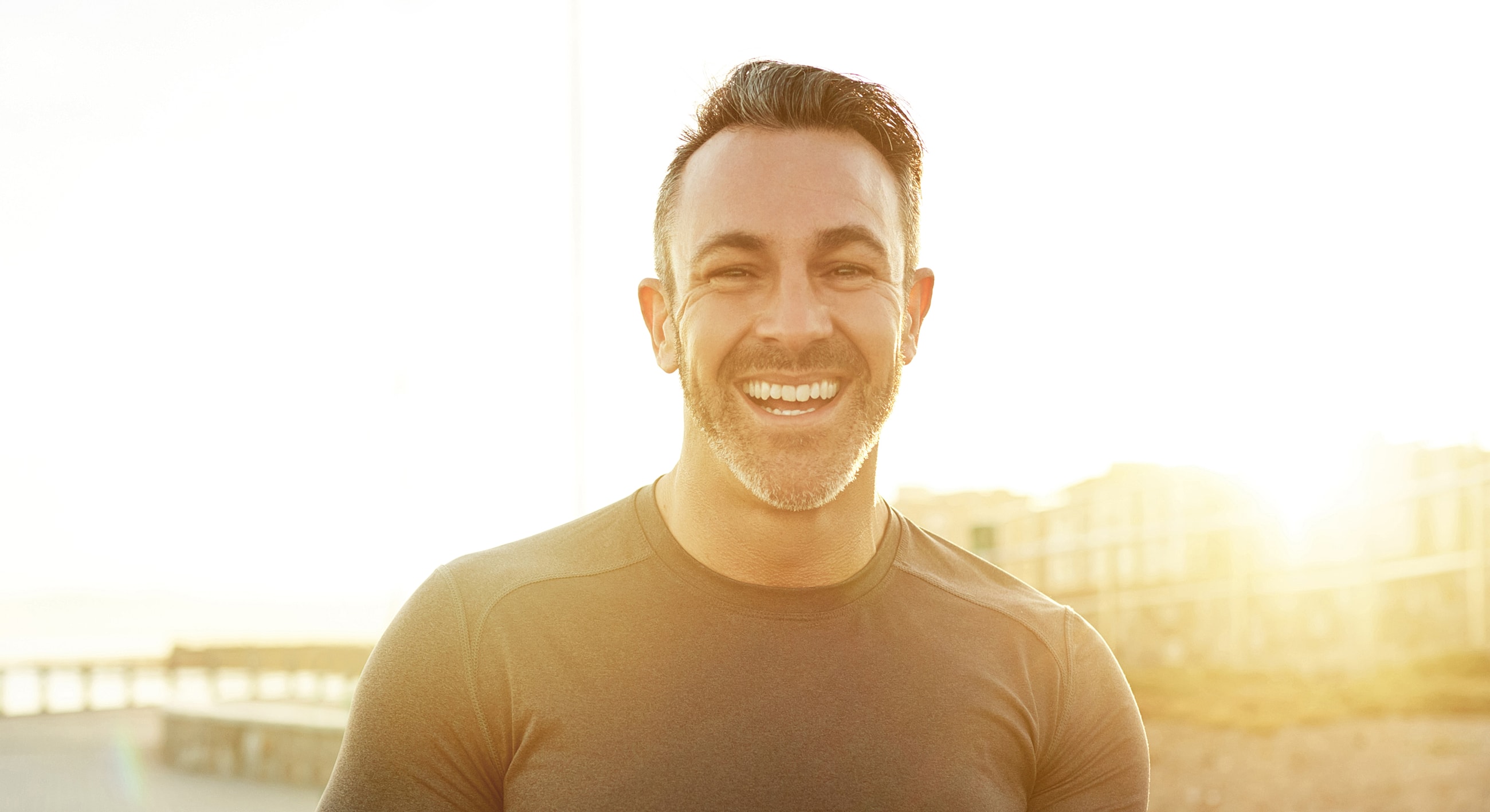 Smiling man in athletic shirt at sunset.