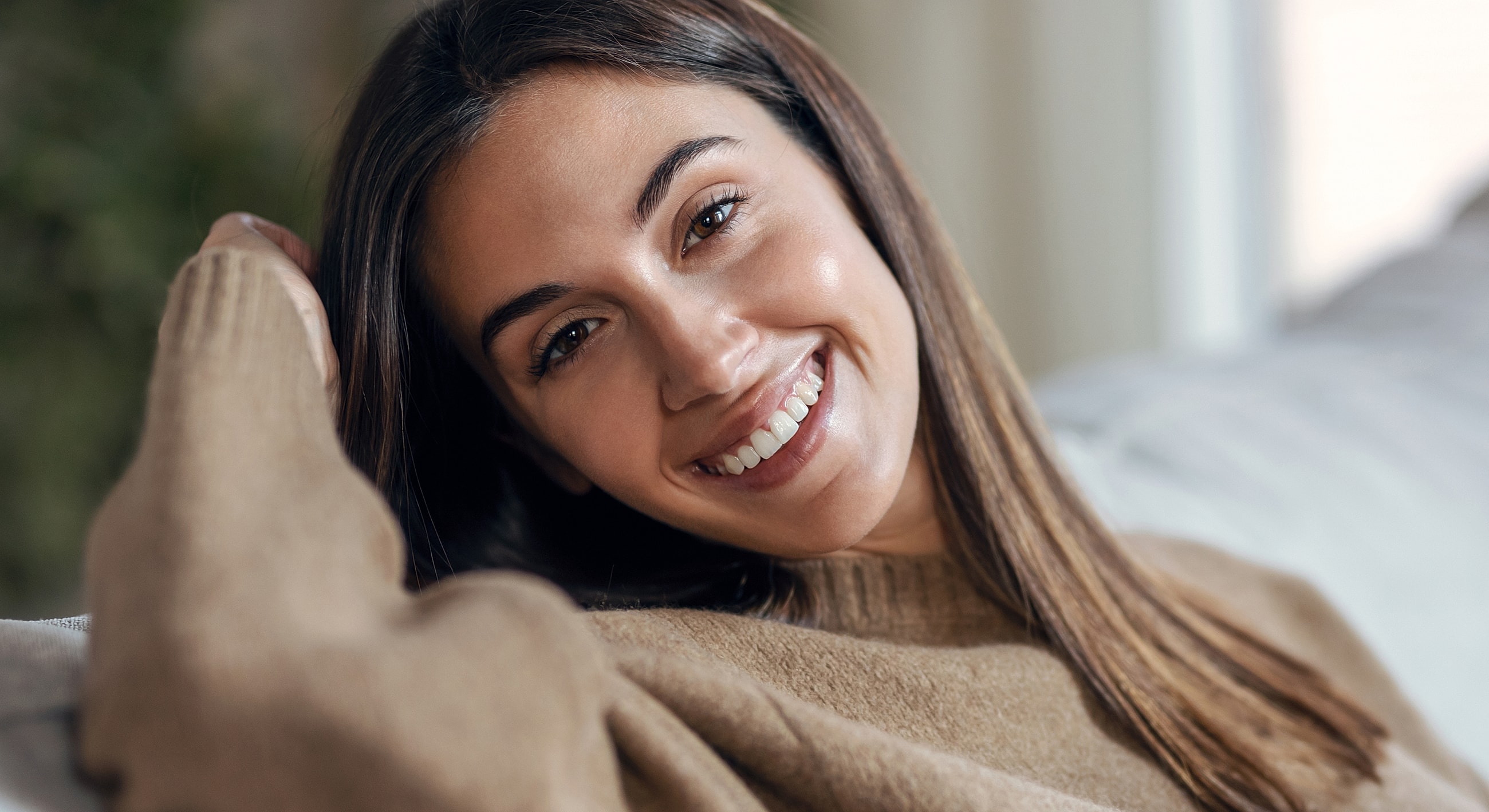Smiling woman sitting on a couch indoors.