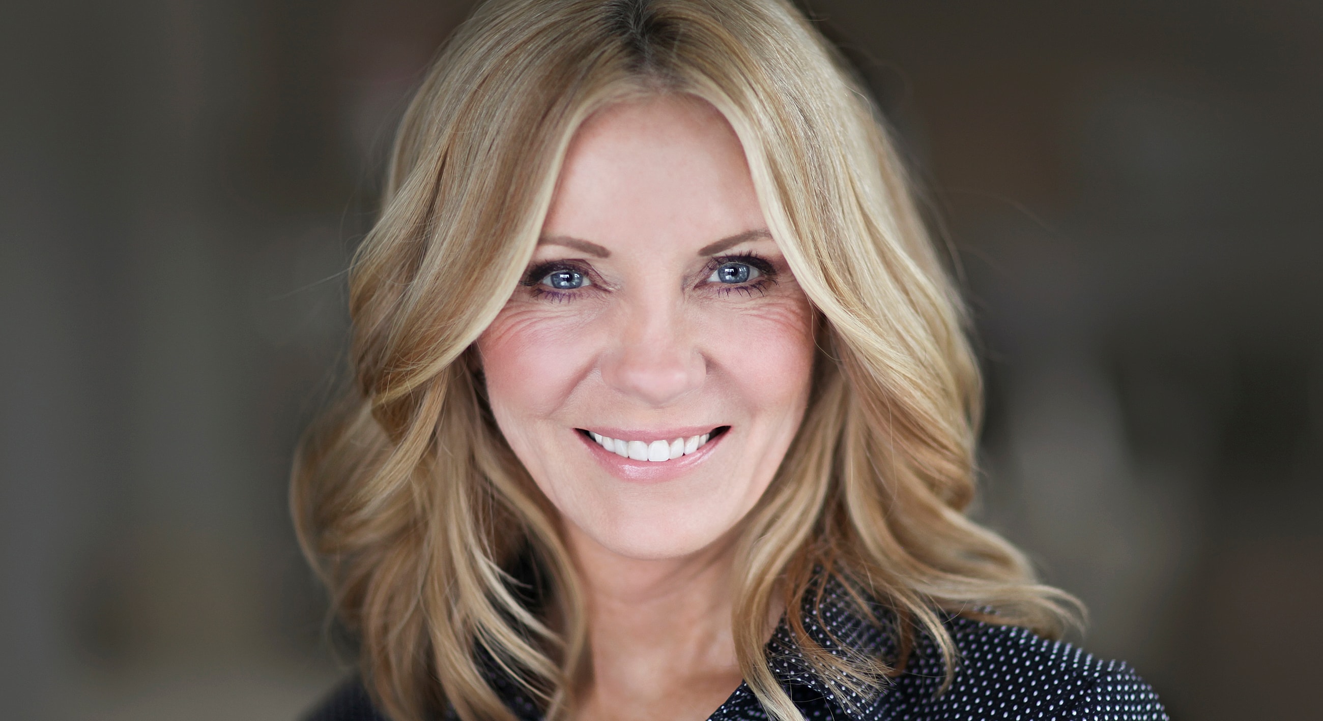 Smiling woman with long, wavy blonde hair.